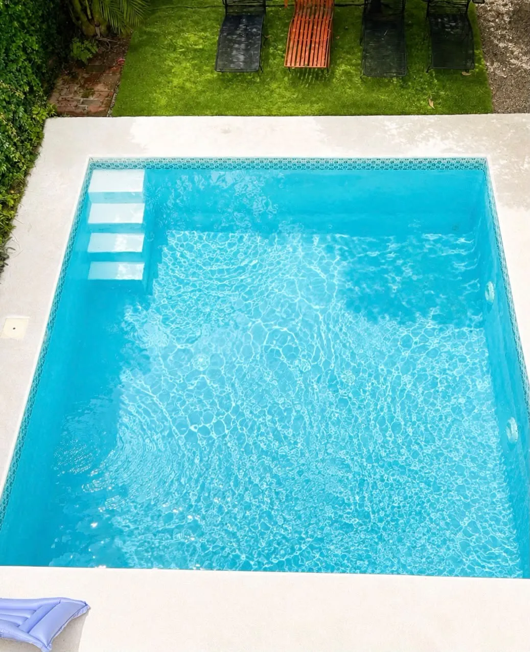 La piscina compartida vista desde arriba, rodeada de jardín.