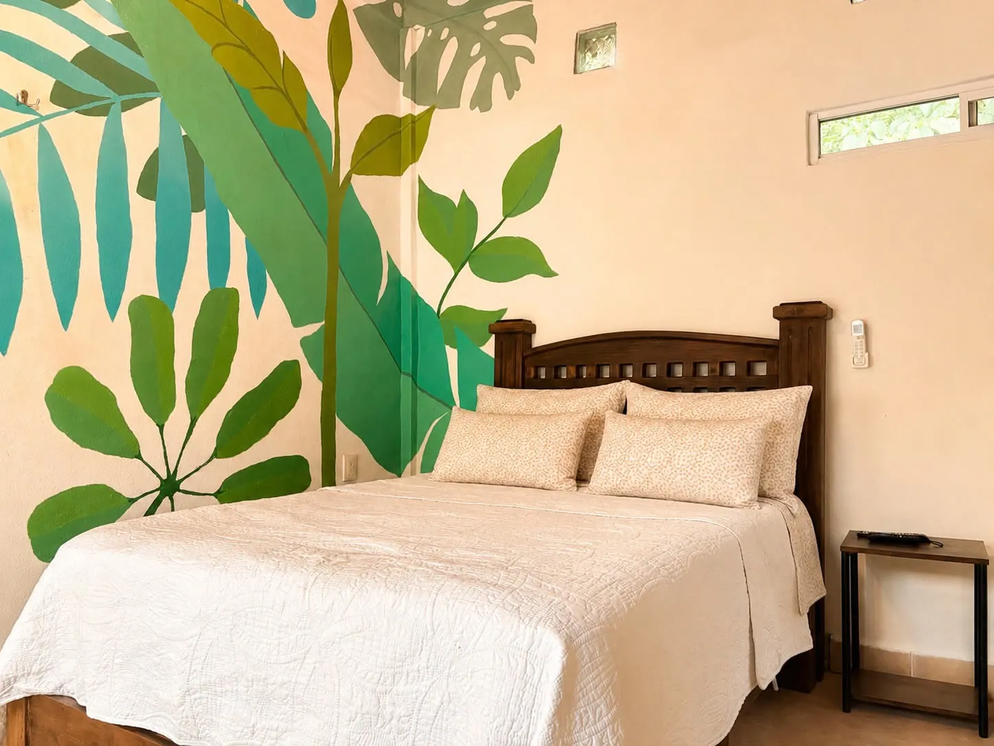 Cama junto a un mural de hojas verdes y plantas naturales.