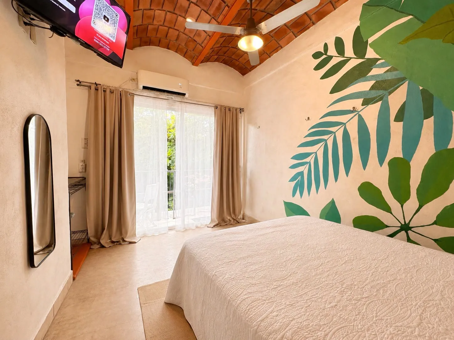 Estudio con techo de bóveda de ladrillo y mural de hojas tropicales.